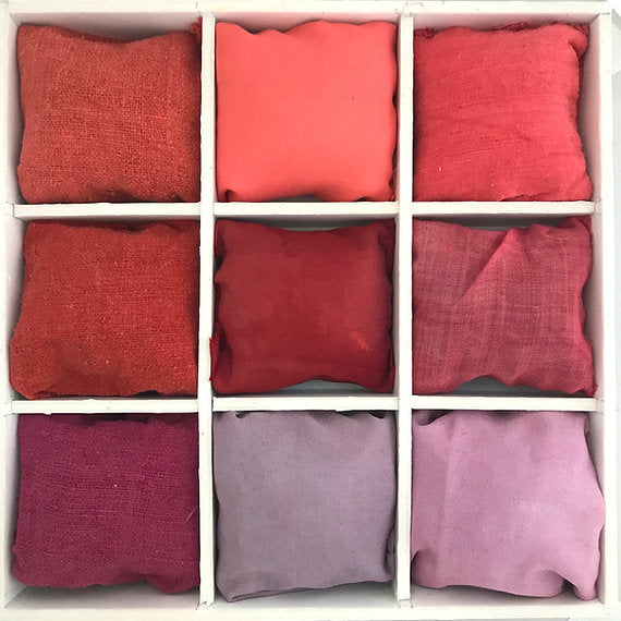 Nine red and pink fabric swatches arranged in a grid on a white background.