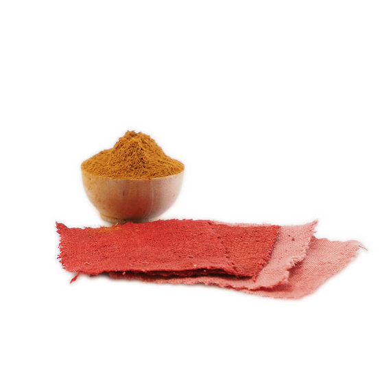 Wooden bowl with red powder and red fabric on a white background