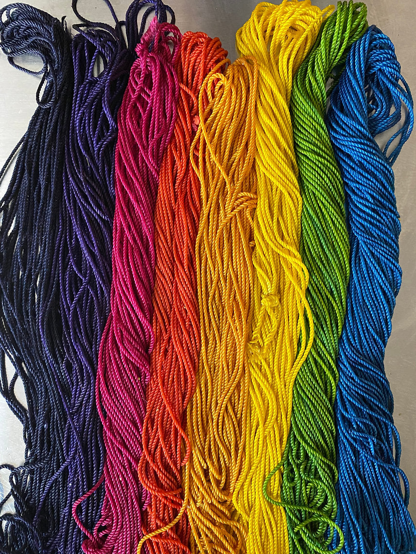 Set of colorful yarn strands in a rainbow sequence on a neutral background