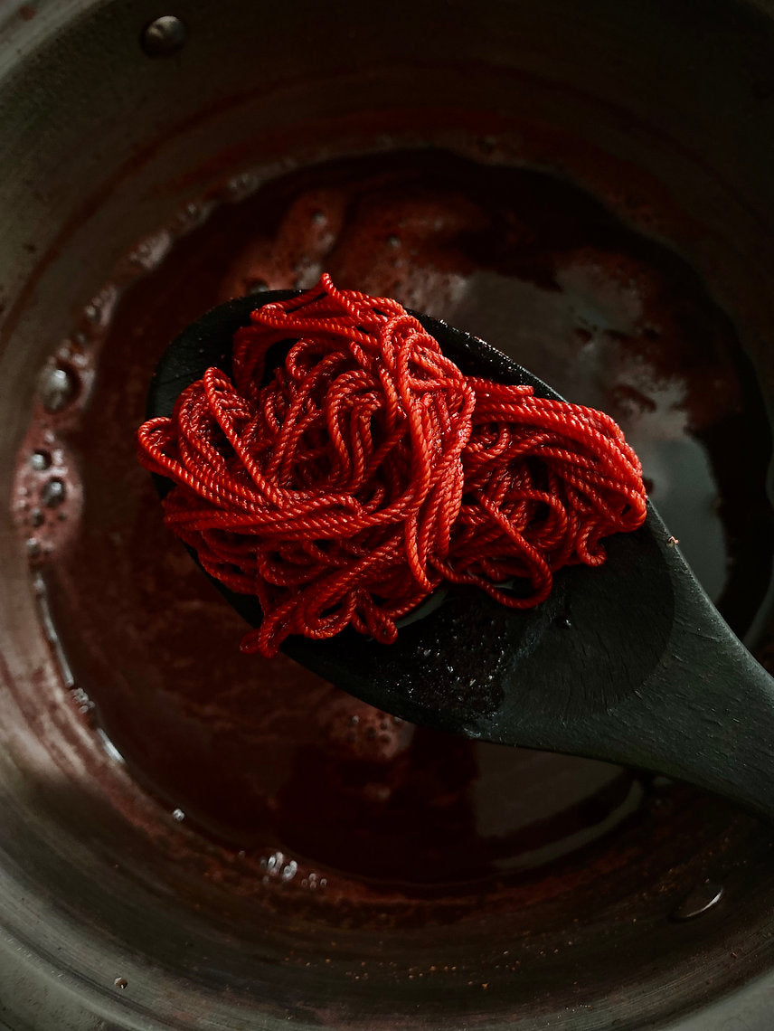 Red yarn on a black spoon over a dark background