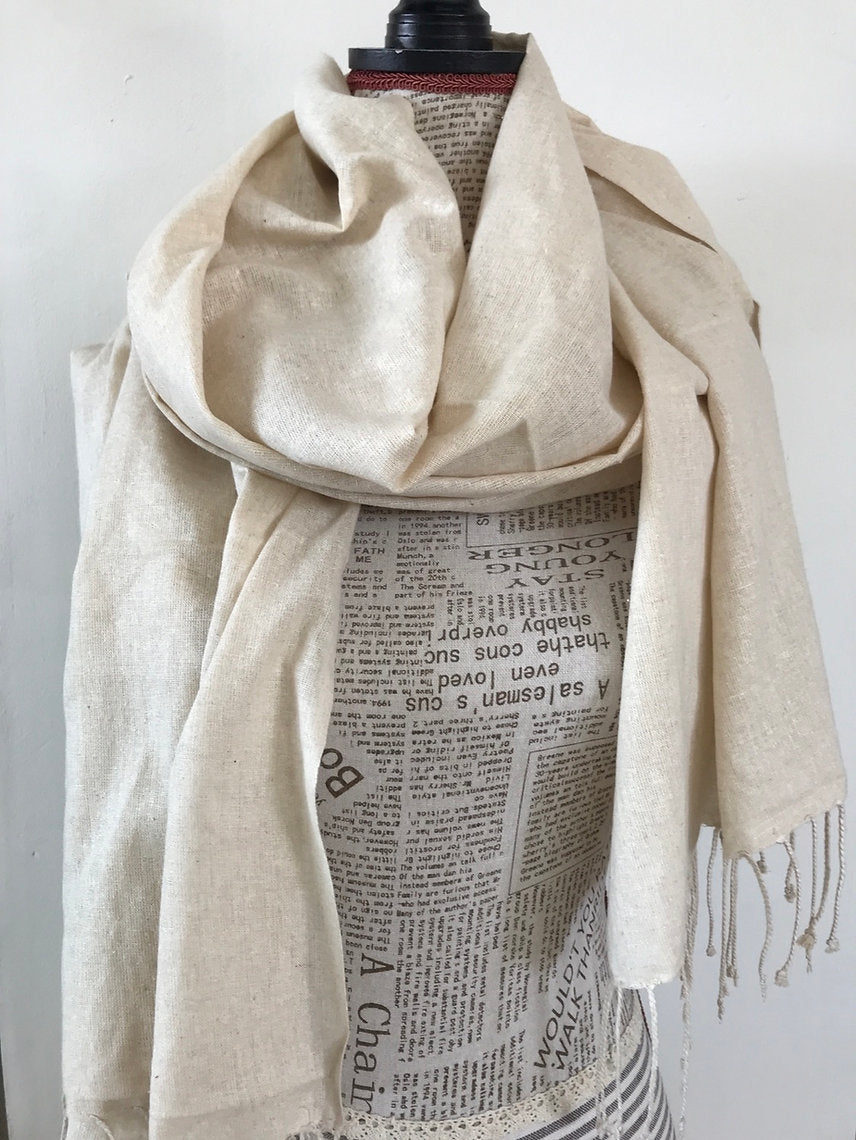 Beige scarf draped over a mannequin with a newspaper pattern against a white background