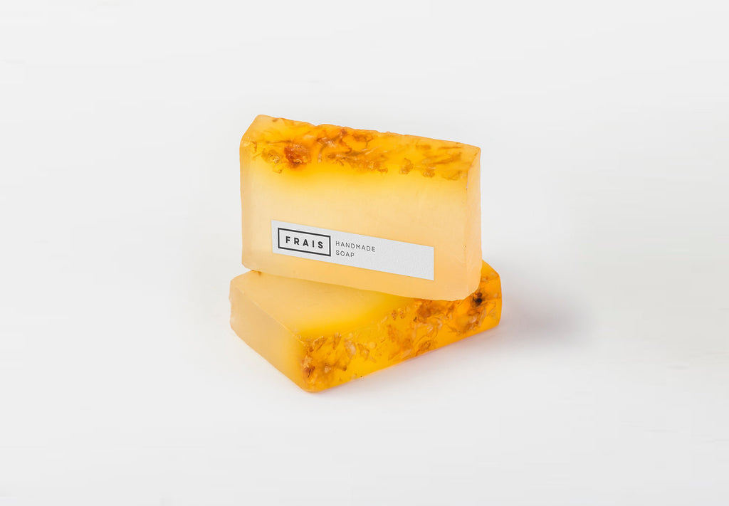 Two yellow St. Johnswort (Hypericum perforatum) organic soap bars with a visible brand label on a white background