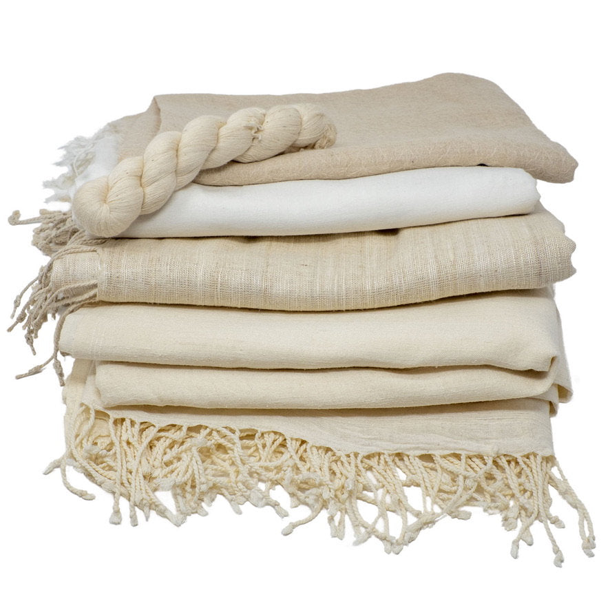 Stack of beige and white shawls towels with fringes on a white background