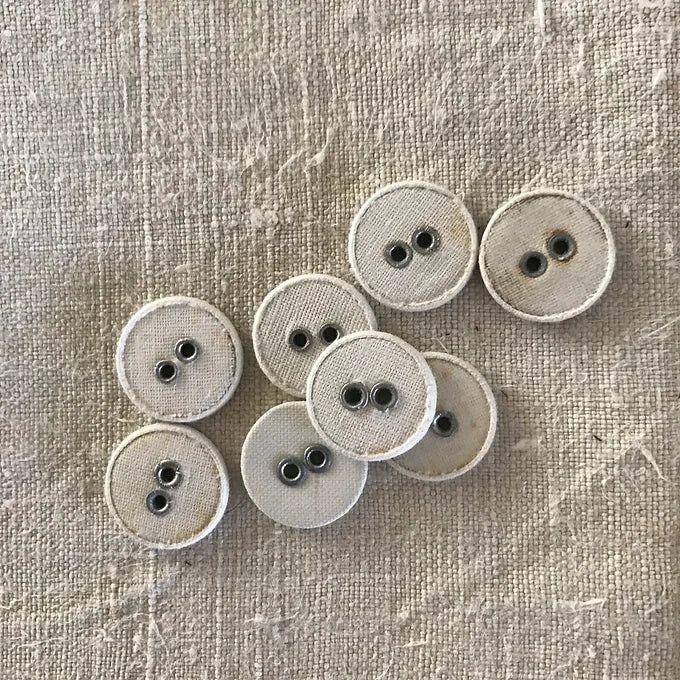 Set of beige buttons with black centers on a textured beige background