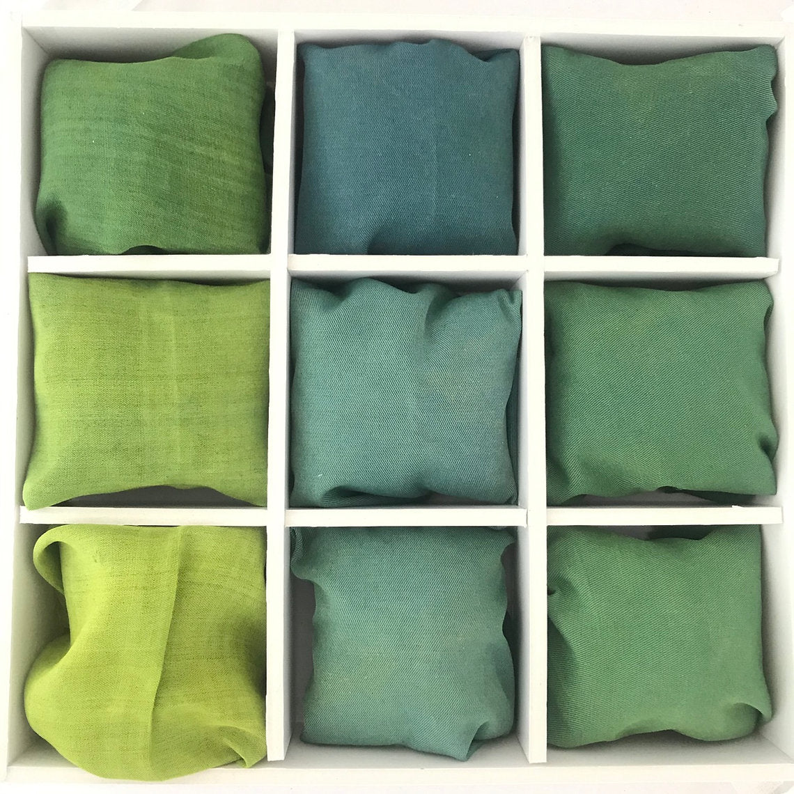 Nine green yellow blue fabrics dyed with Weld (Reseda Luteola) Organic Powder arranged in a 3x3 grid on a white background