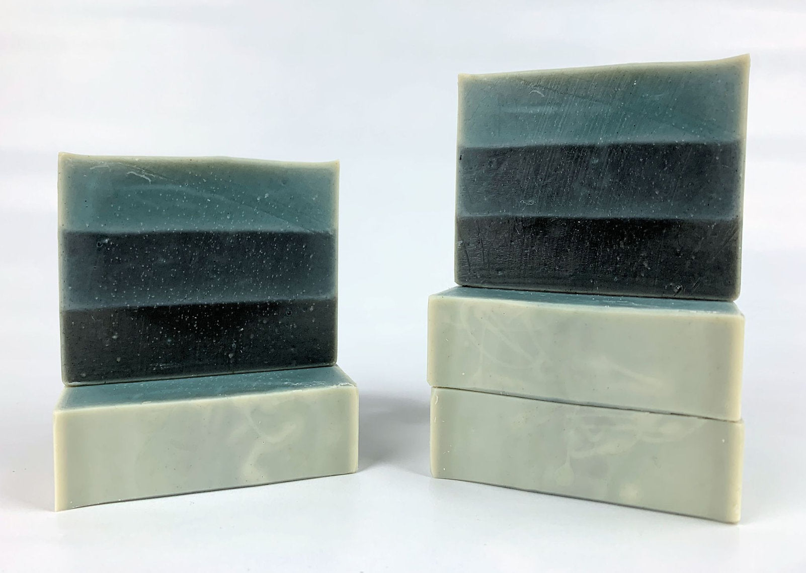 Three bars of layered Woad (Isatis Tinctoria) soap on a white background