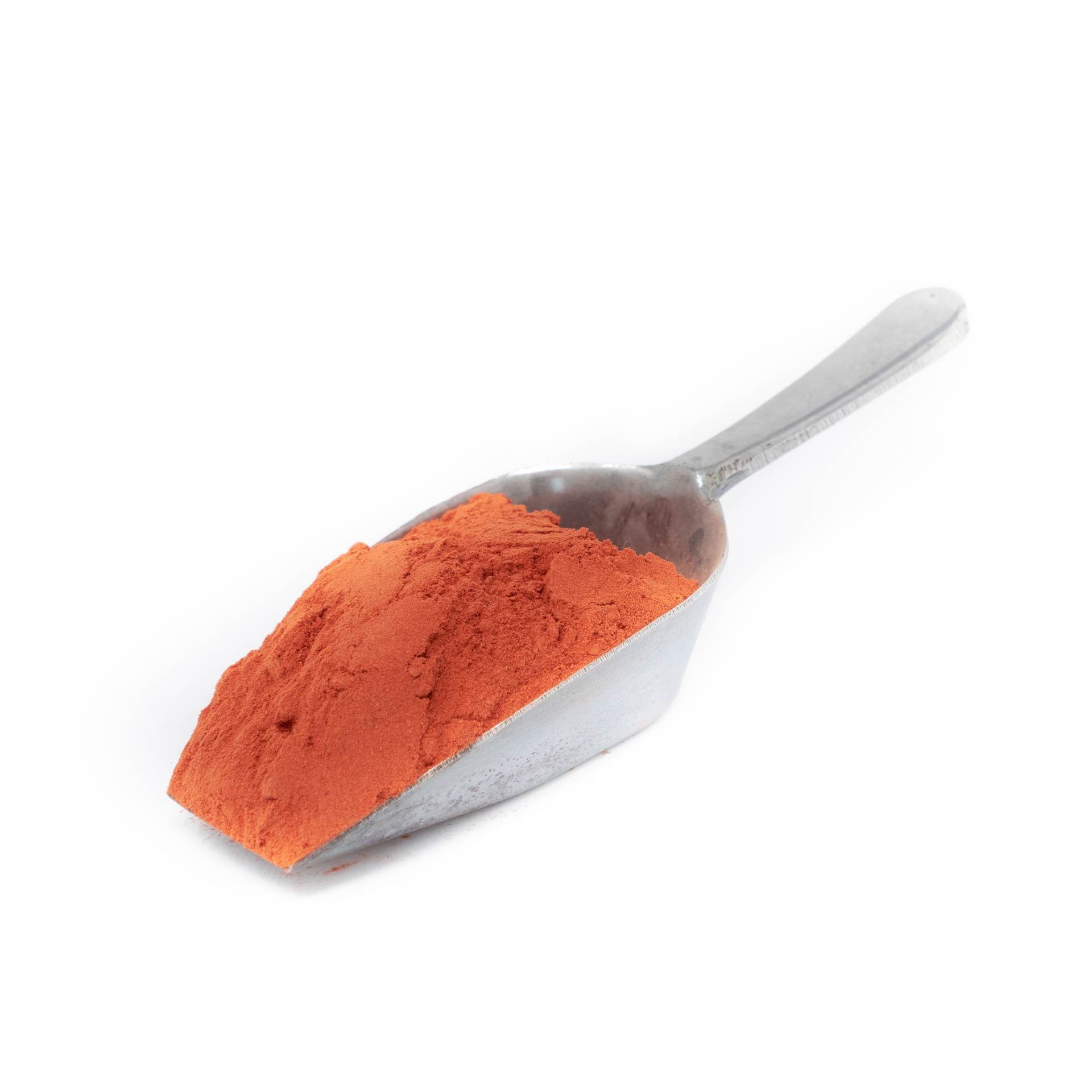 Metal scoop filled with orange powder on a white background