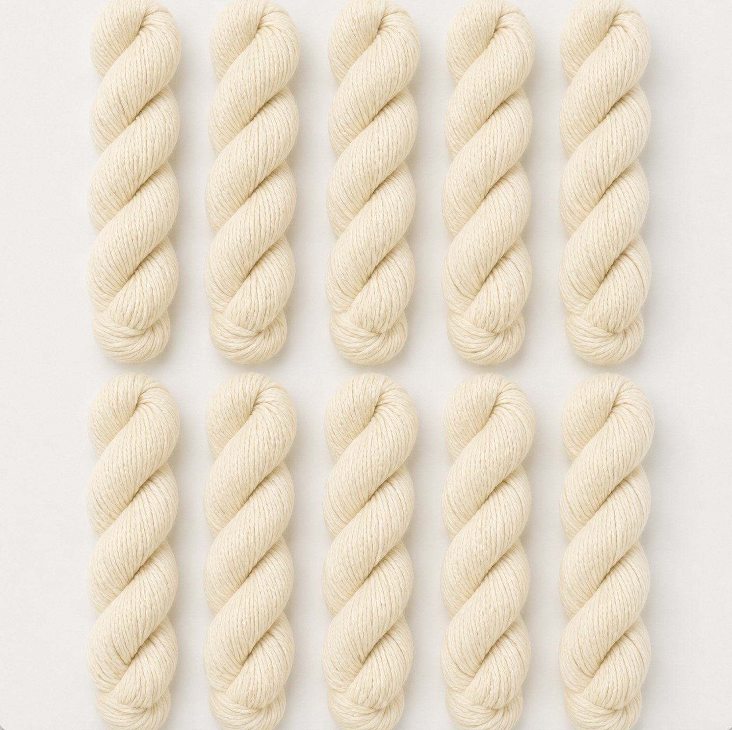 Nine skeins of cream-colored yarn arranged in a 3x3 grid on a light gray background.